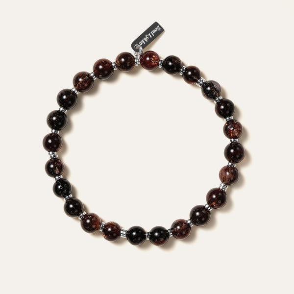 The Eclipse Gold bracelet by Soul Lykke in natural light. Featuring collector-grade 6mm AAA Black Gold Super Seven and high-polished 925 sterling silver spacers, this piece commands an enigmatic, near-solid black presence for understated luxury. This is a natural gemstone and healing crystal bracelet by Soul Lykke.